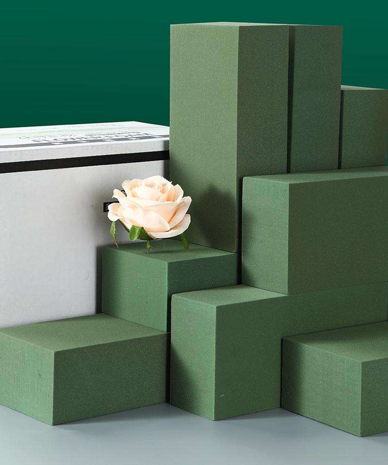 Tiered green floral foam blocks with a single peach rose against a dark green background.